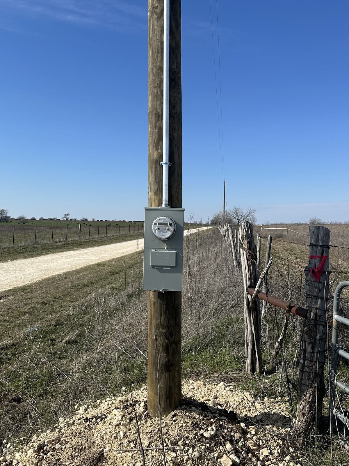 New electrical meter and disconnect mounted on a pole beside a ranch road in rural North Texas